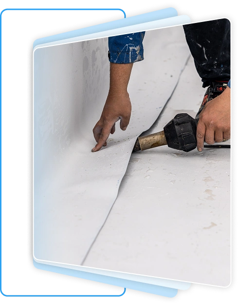 Worker applying heat to seal a flexible white waterproof surface membrane.