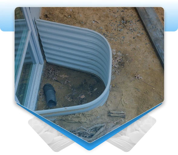 Corrugated metal basement window well with drainage pipe installed outside a home.