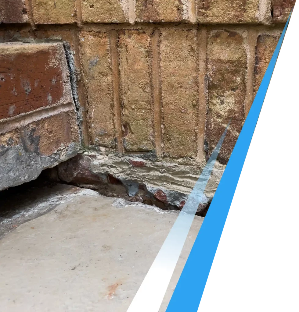 Severe foundation settling showing a large crack between exterior brickwork and a sinking concrete slab.