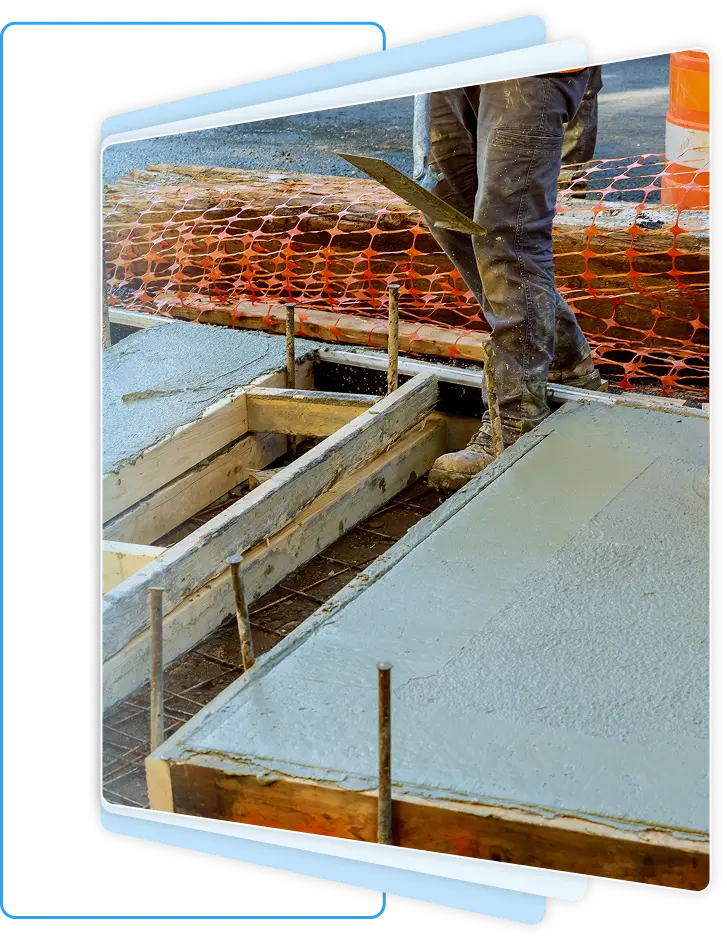 Construction worker holding a finishing trowel while standing next to freshly poured and smoothed concrete flatwork secured by wooden formwork.