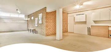 Basement renovation space showing exposed red brick walls alongside newly built structural framing.