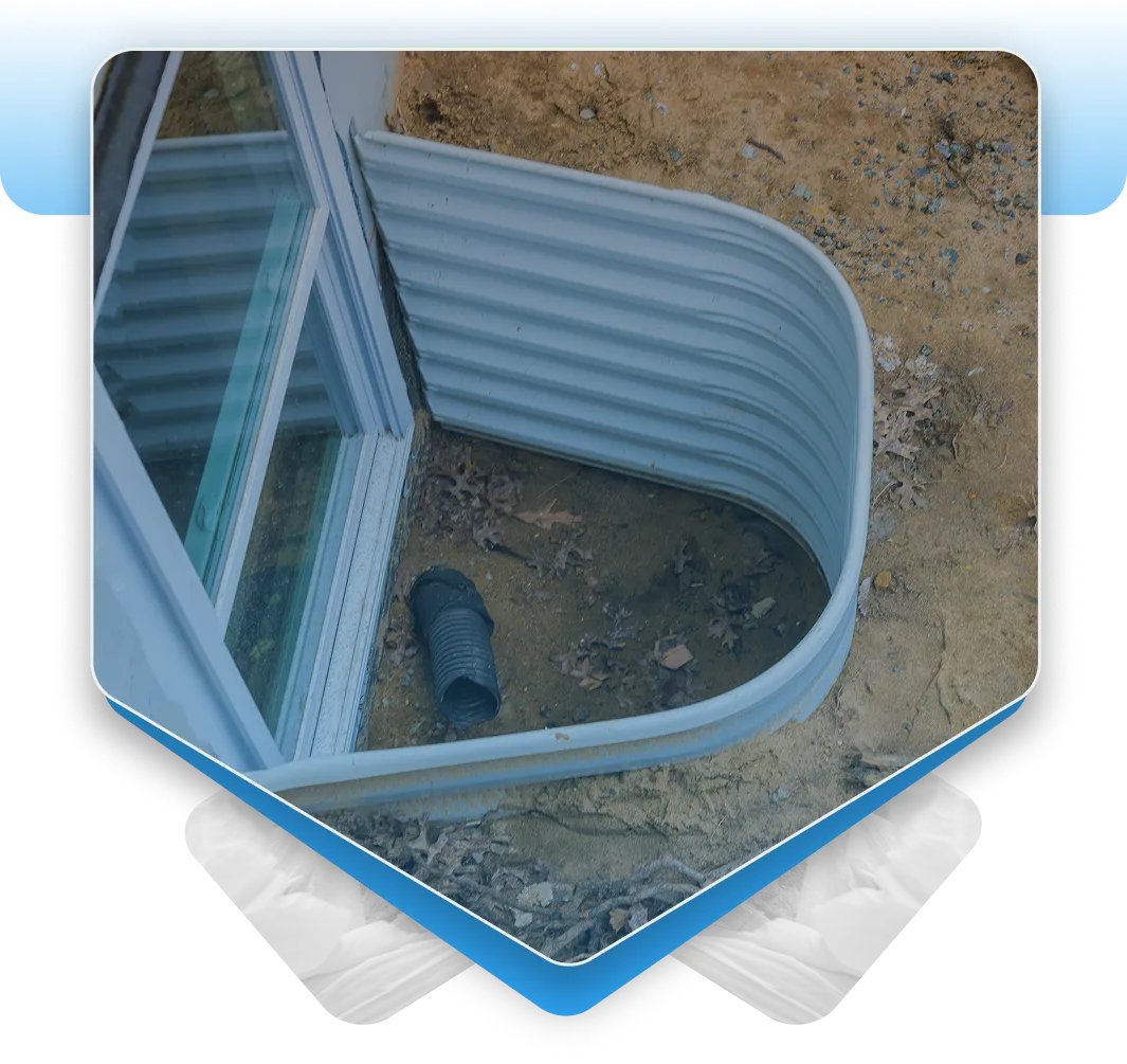 Metal window well with an exposed black drain pipe.