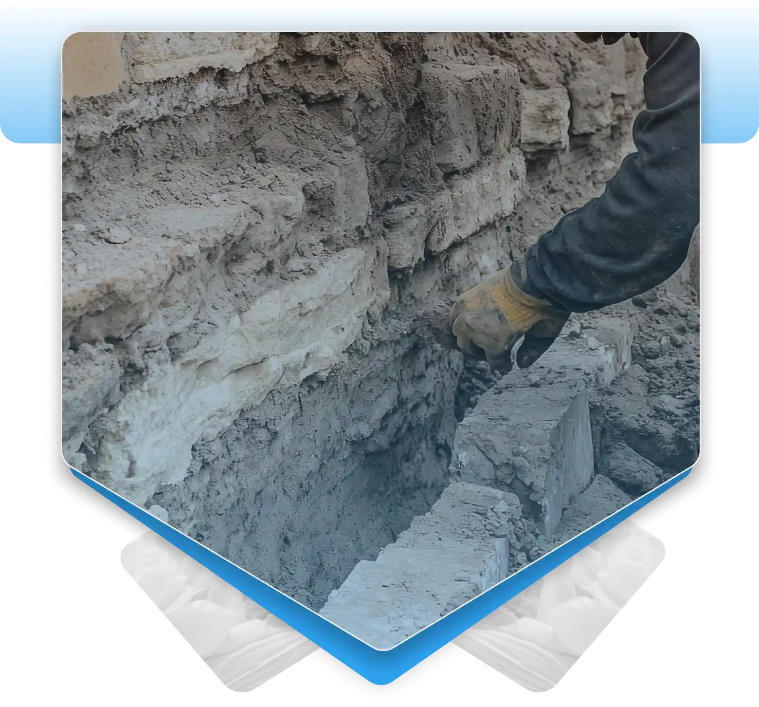 Worker repairing an old stone foundation wall with mortar in an excavated trench.