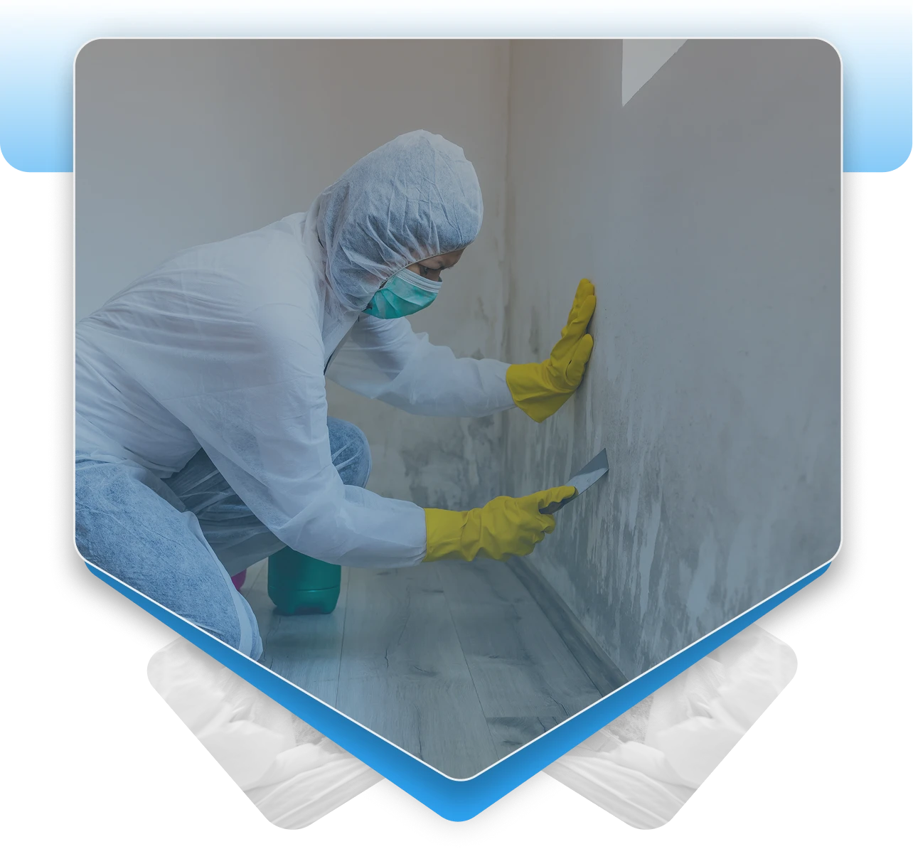 Worker in a hazmat suit scraping a moldy wall.