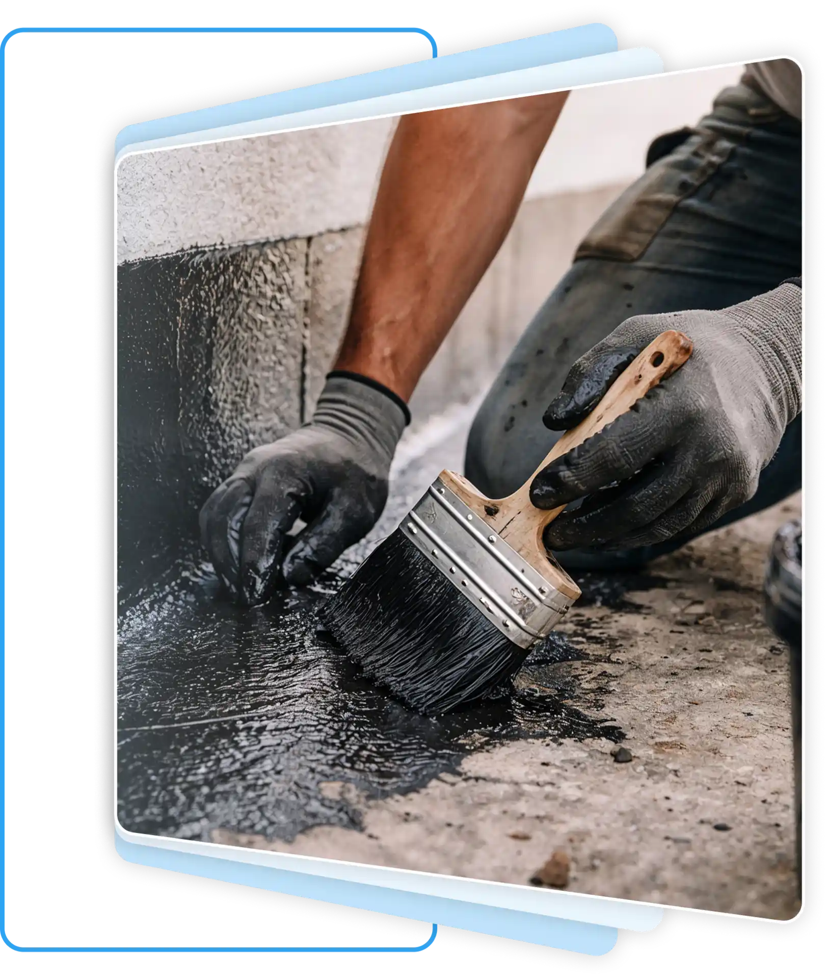 Applying black waterproofing sealant to a concrete foundation.
