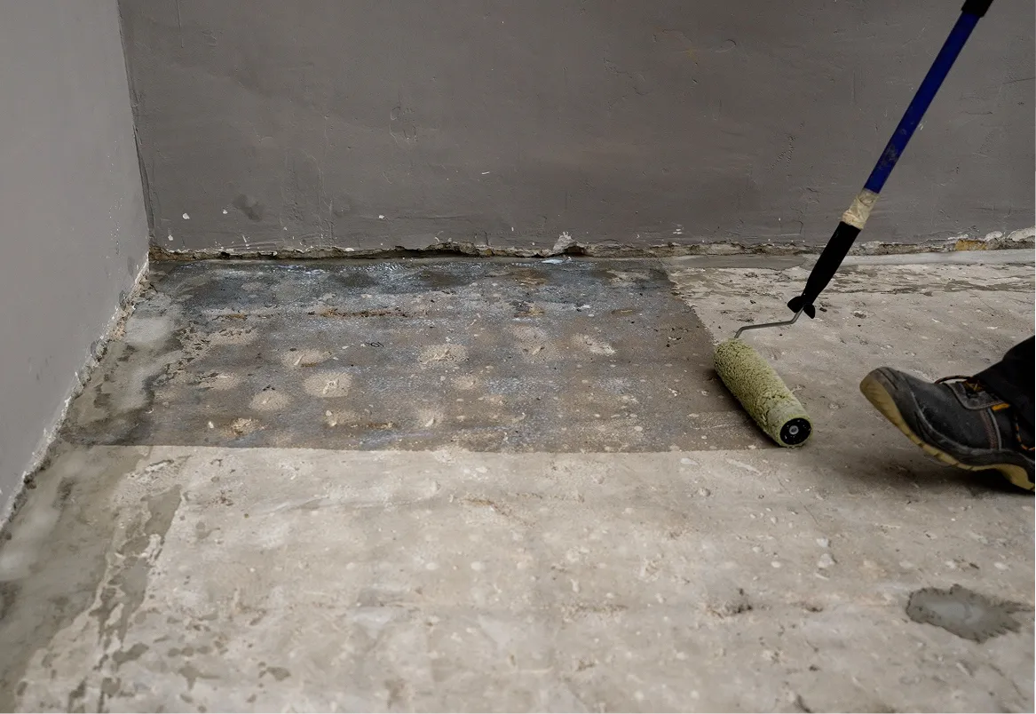 Applying sealant to a concrete floor using a paint roller.
