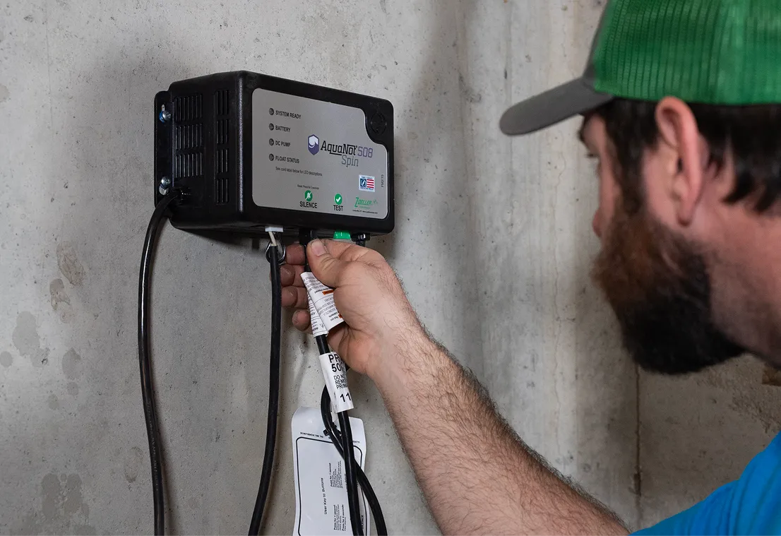Plumber testing a battery backup control box on a sump pump installation.